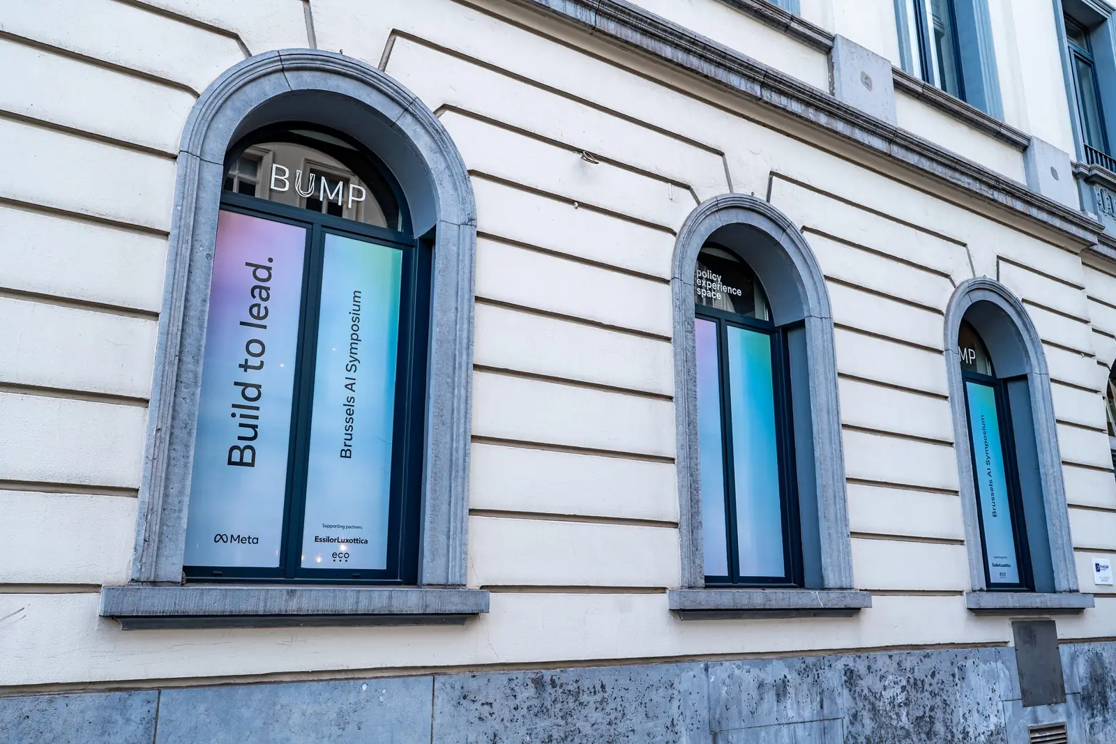 The Bump Policy Experience Space from the street, its arched windows dressed &ldquo;Build to lead.&rdquo; for the Brussels AI Symposium