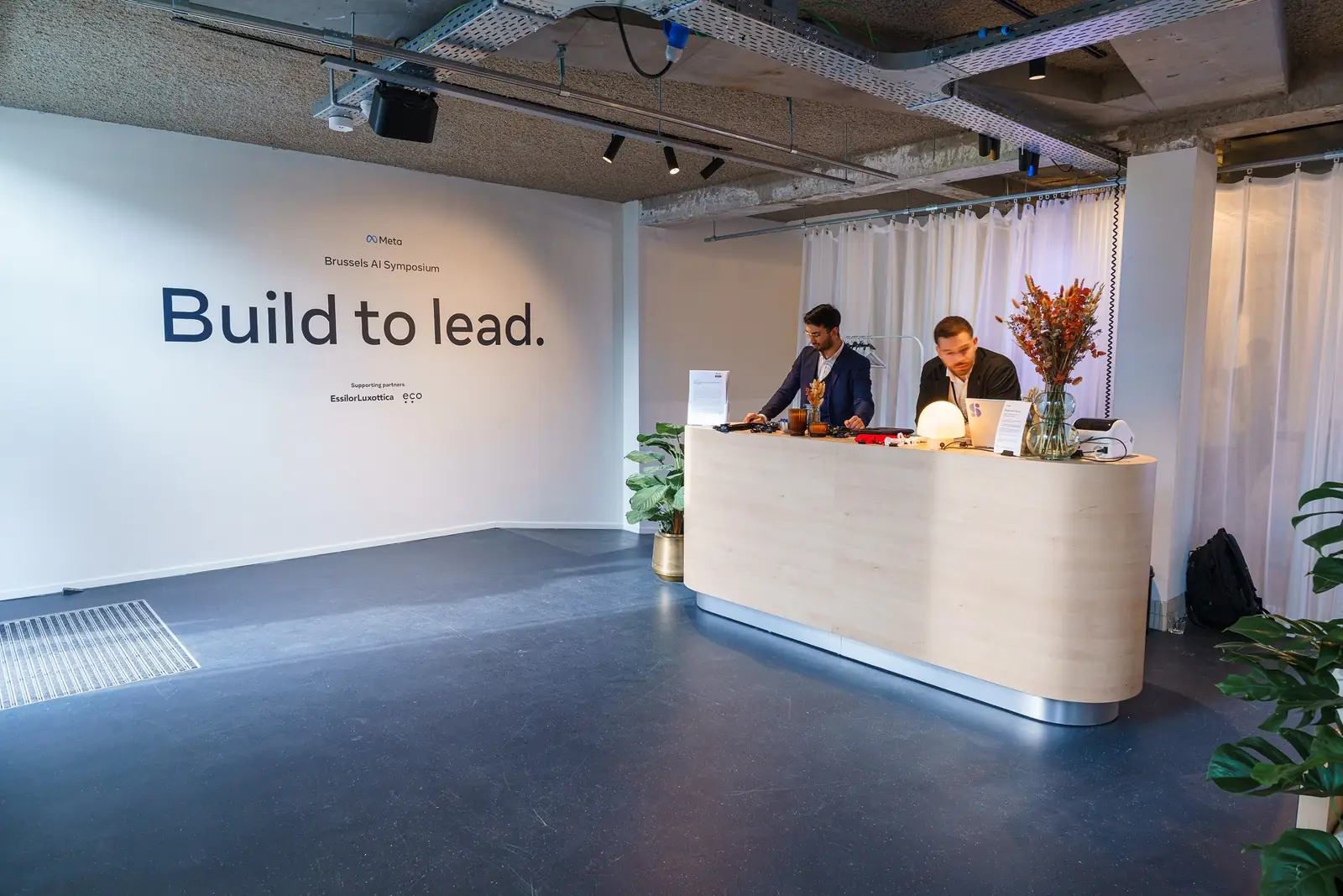 The welcome desk beneath a wall reading &ldquo;Build to lead.&rdquo;