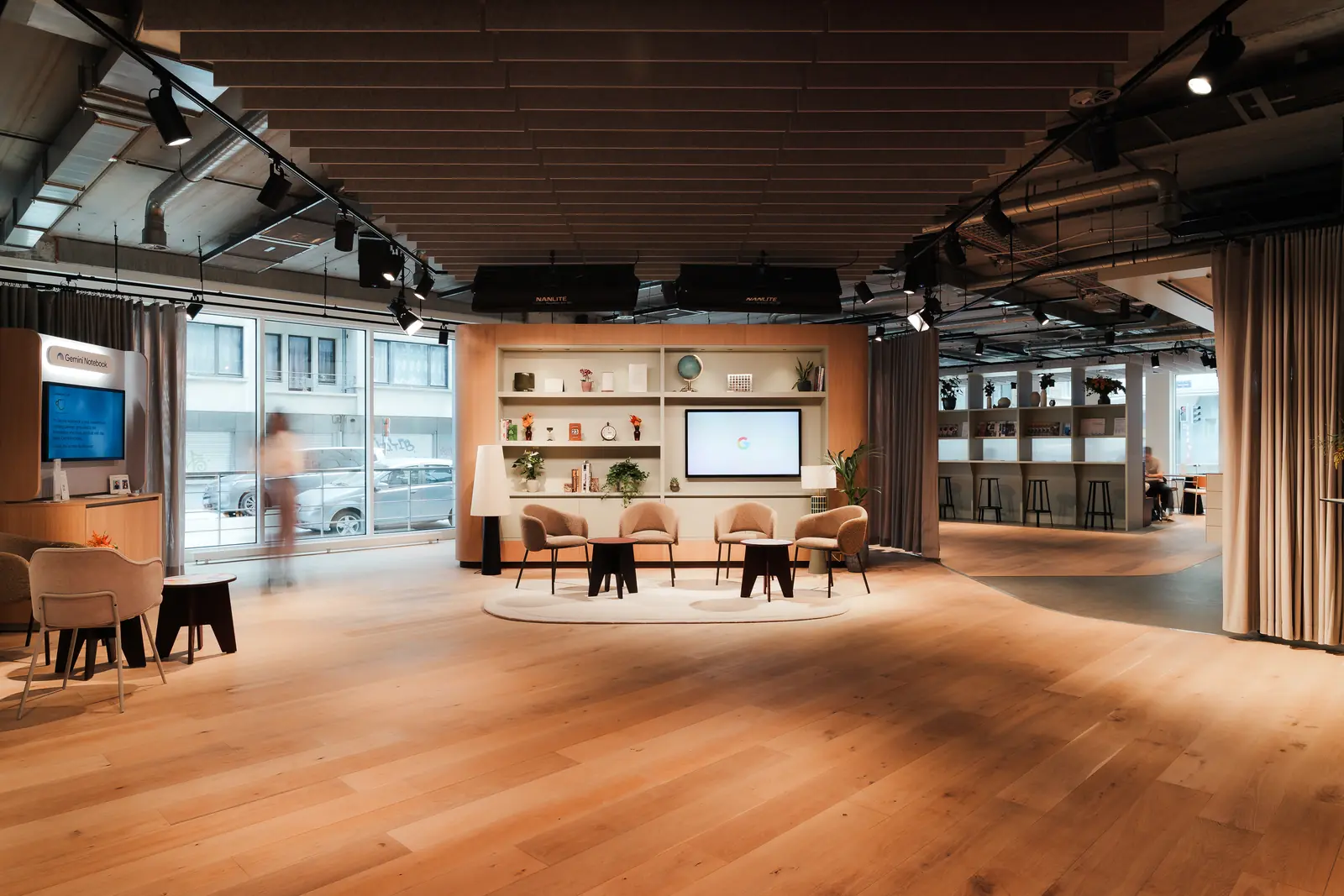 The room set as a lounge, with armchairs around a low table facing a screen and open shelving