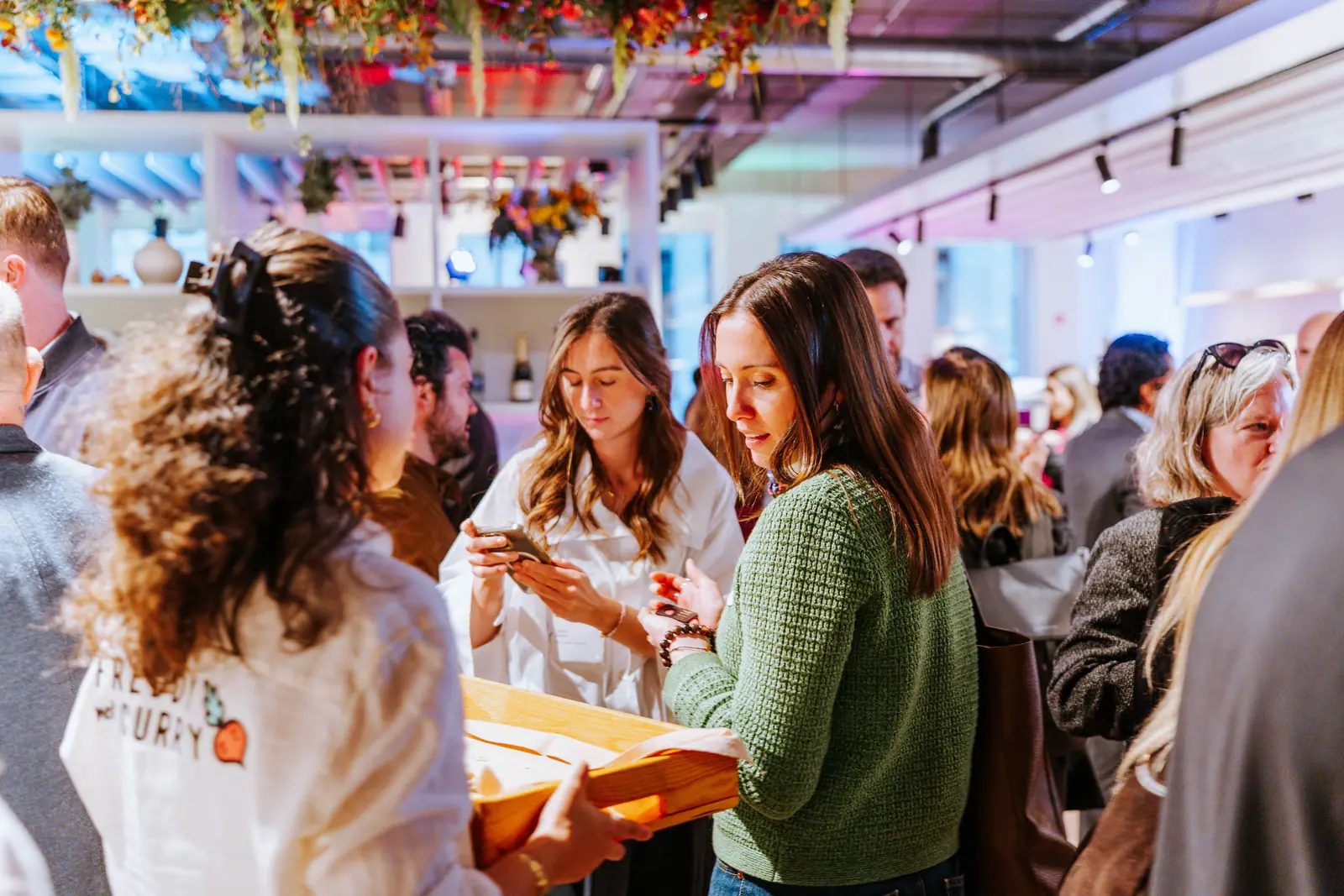 Guests talking over drinks at an evening reception, under hanging florals