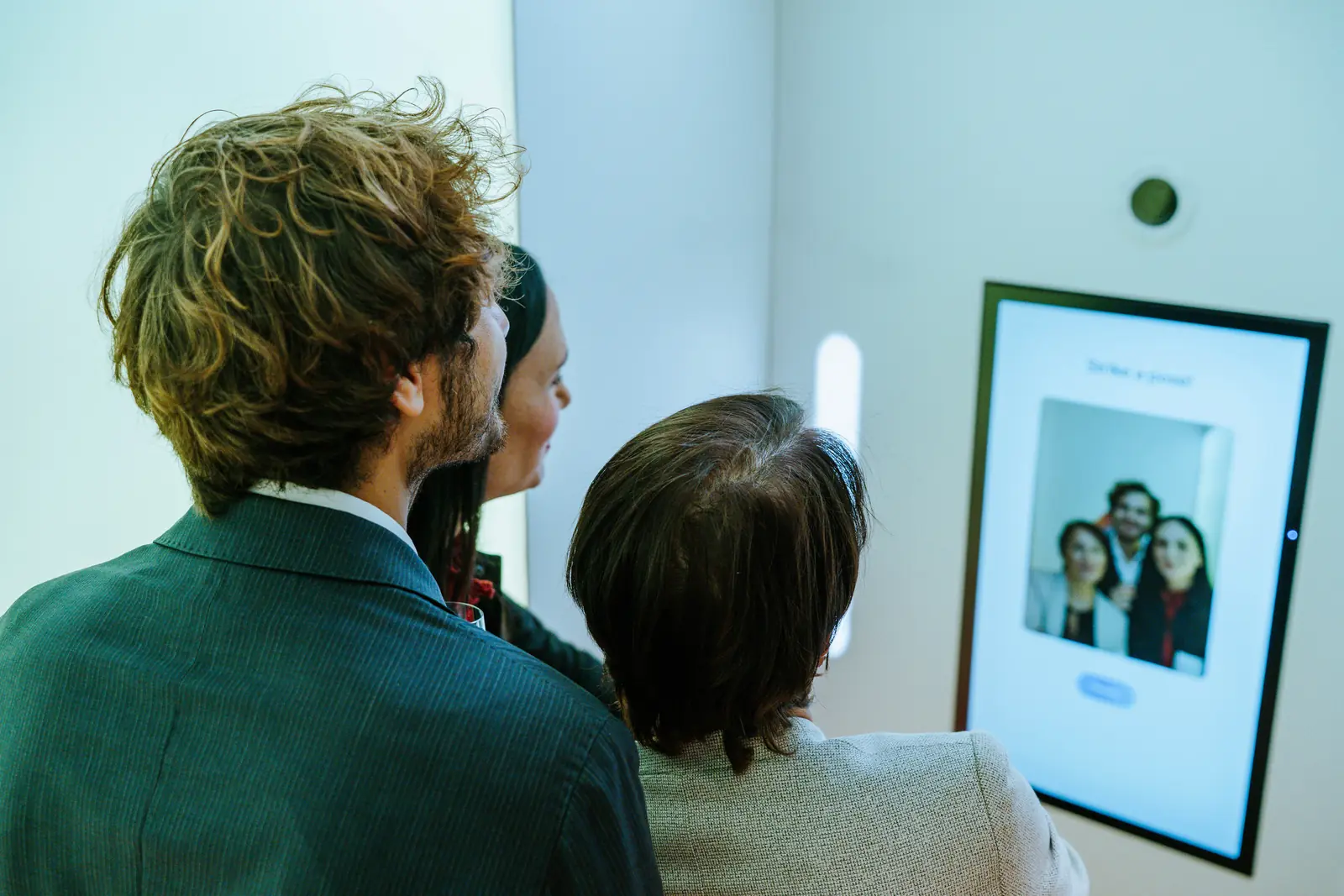 Three guests at the AI photo booth, looking at the portrait it has just made