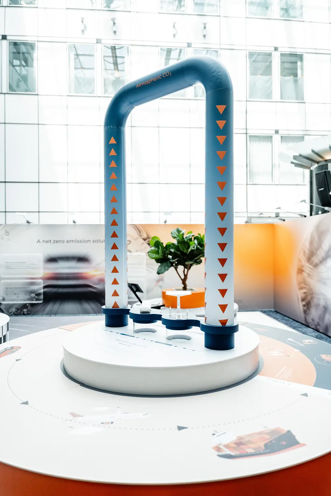 A blue pipe sculpture with orange arrows tracing the net zero CO2 cycle