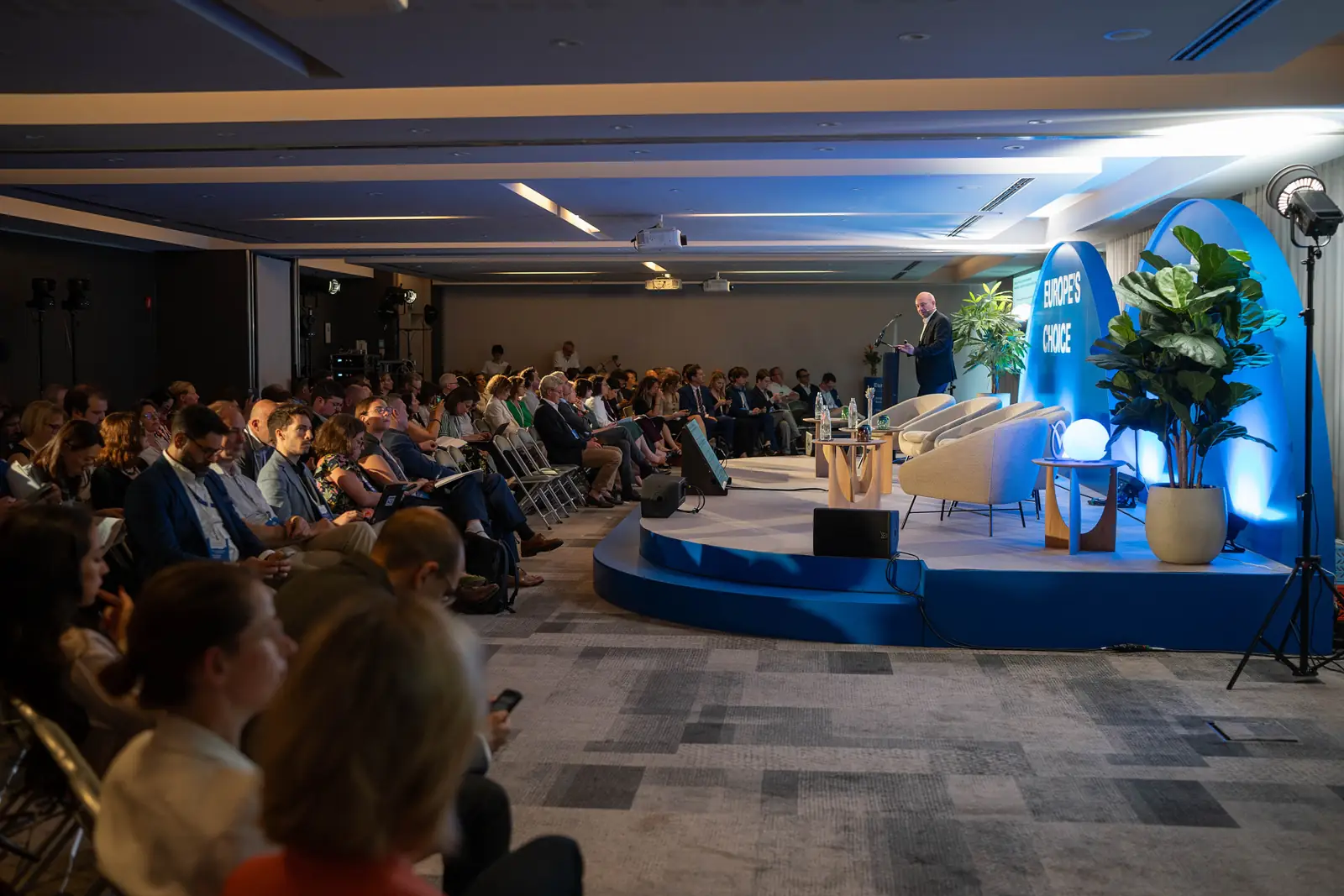 A speaker at the lectern addressing a full room
