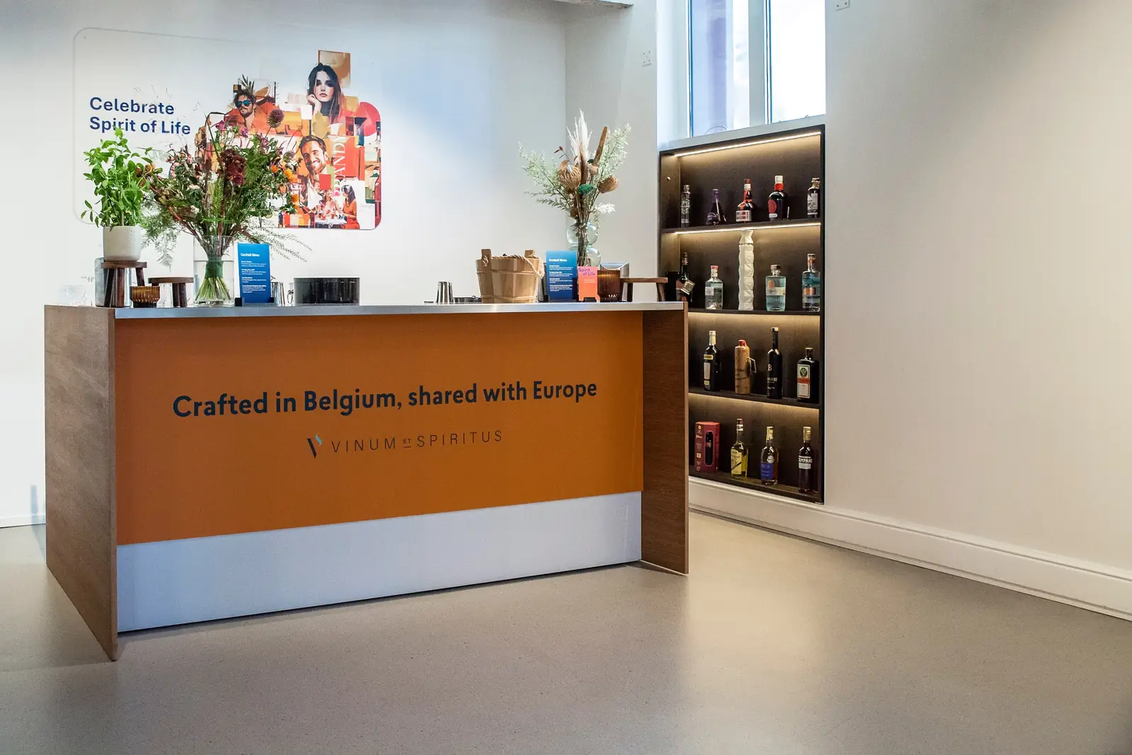 A bar counter reading &ldquo;Crafted in Belgium, shared with Europe&rdquo;, with Belgian spirits on the shelves behind