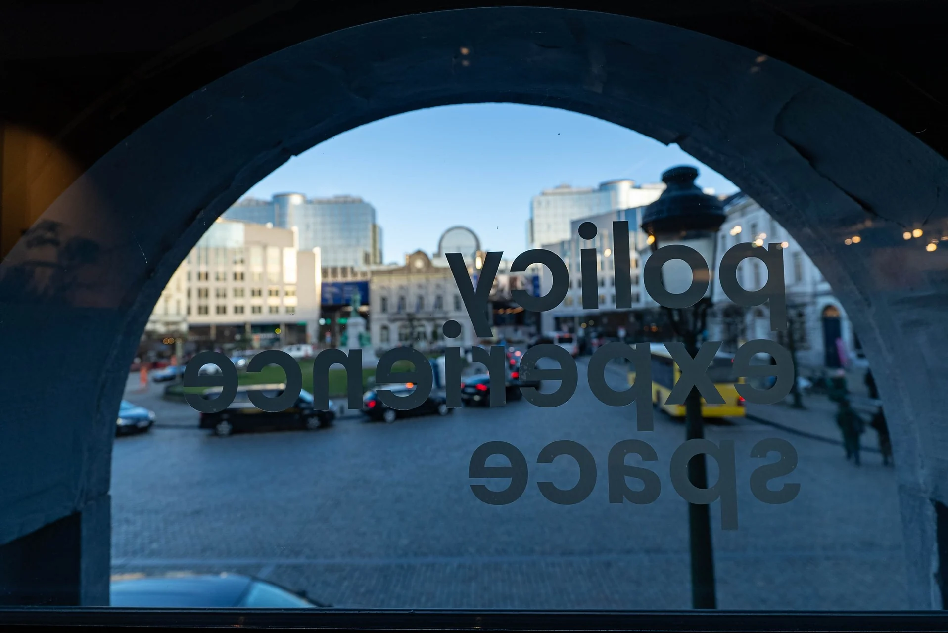 Place du Luxembourg seen from inside the Bump Policy Experience Space, through an arched window lettered “policy experience space”